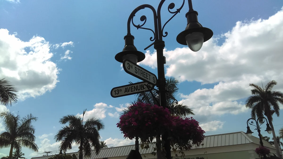 Third Street South and Thirteenth Avenue South signs above flower baskets and district buildings in Naples